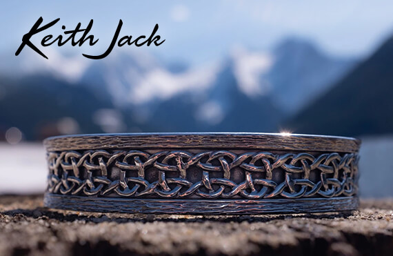Keith Jack Jewelry - image of a Keith Jack wedding band with celtic knotwork in front of a blurred mountain scape